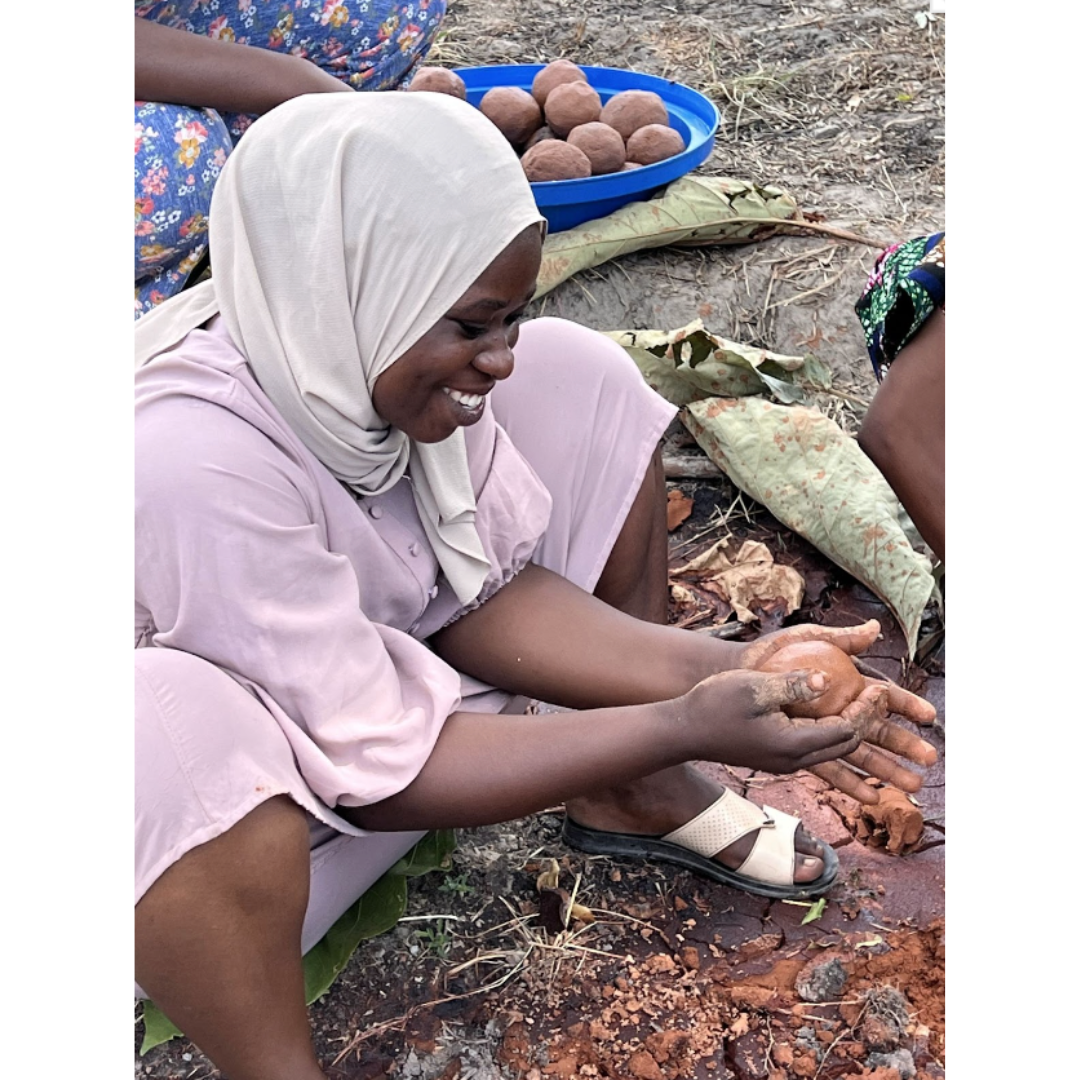 Memuna, hand-shaping a traditional fuel ball from shea waste