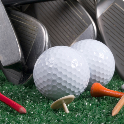 photo of golf balls, tees, a ball marker, and clubs laid on a green