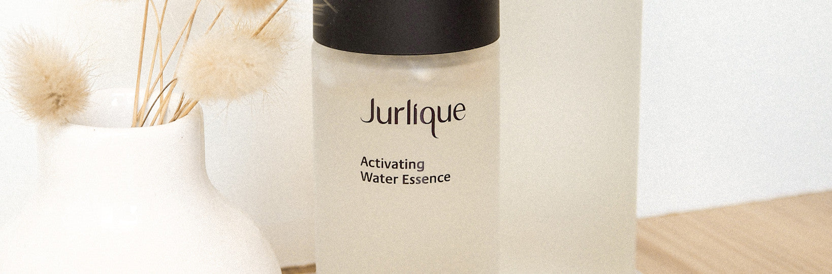 Bottle of Jurlique Activating Water Essence next to plant in a white vase