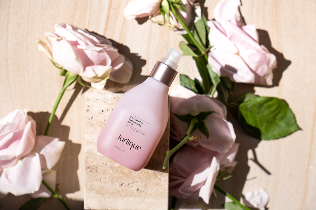 Bottle of Jurlique Rosewater Balancing Mist next to pink roses