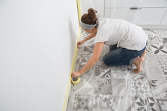 woman installing tape around room trims for paint preparation