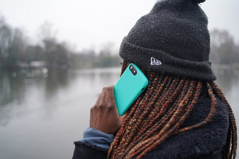 Person using Apple iPhone 12 in a reboxed eco phone case against the backdrop of a lake