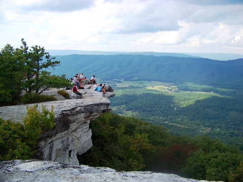 Hikers sitting on cliff ledge overlooking the Catawba Valley