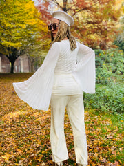 Outfit shot of person wearing white floaty angel wing top lookin left