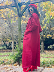 Outfit shot of person wearing long red coat facing left with side to the camera