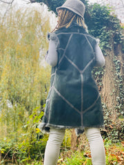 Outfit shot of person wearing grey fur waistcoat and glasses facing away from camera