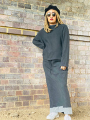 Outfit shot of person wearing grey jumper and skirt facing camera