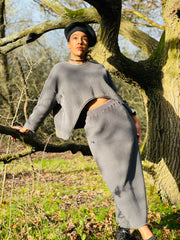 Outfit shot of person wearing matching grey skirt and jumper posing against a tree facing camera