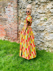 Outfit shot of person wearing multi-colour gown and headscarf and sunglasses facing the side