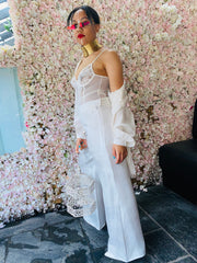 Outfit shot of person wearing white trousers and blouse facing left