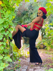 Outfit shot of person wearing black thigh slit trousers with red detailing posing facing left