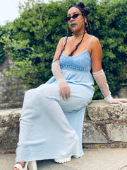 Outfit shot of person wearing long blue dress with beaded top sat down facing the camera