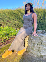 Portrait photo of person wearing rented green maxi dress sitting down