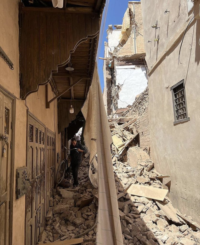 Man walking a bicycle over rubble in the wake of the September 8th 2023 earthquake damage in Marrakech medina