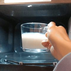 boomerange of a clear glass mug containing skim milk being put into a microwave