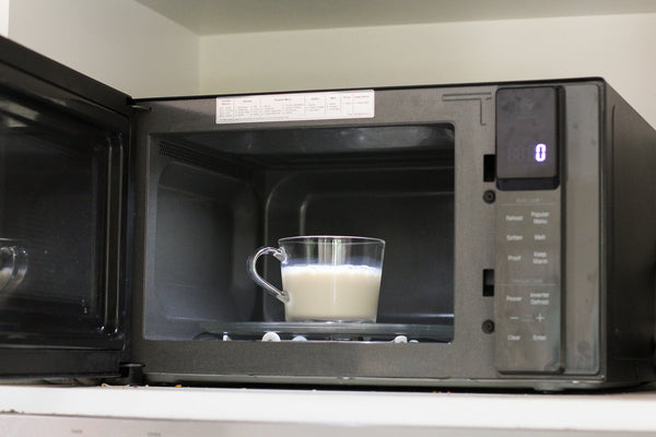 unsweetened oat milk in a mug in a microwave