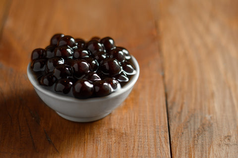 freshly cooked tapioca pearls in white glass bowl on wooden table looking glossy af