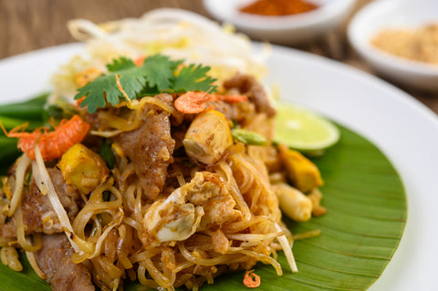 pad thai white plate with lemon eggs seasoningn wooden table