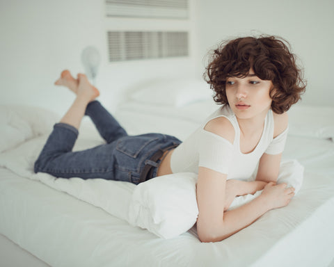 woman with curly hair lying on bed
