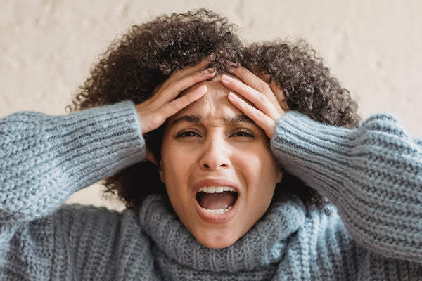 woman with curly hair in sweater frustrated