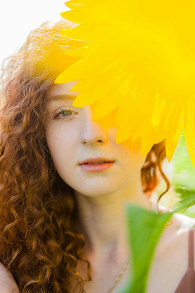 woman outdoors with curly hair and a flower