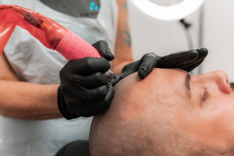 A cosmetic tattoo technician is performing an SMP tattoo procedure