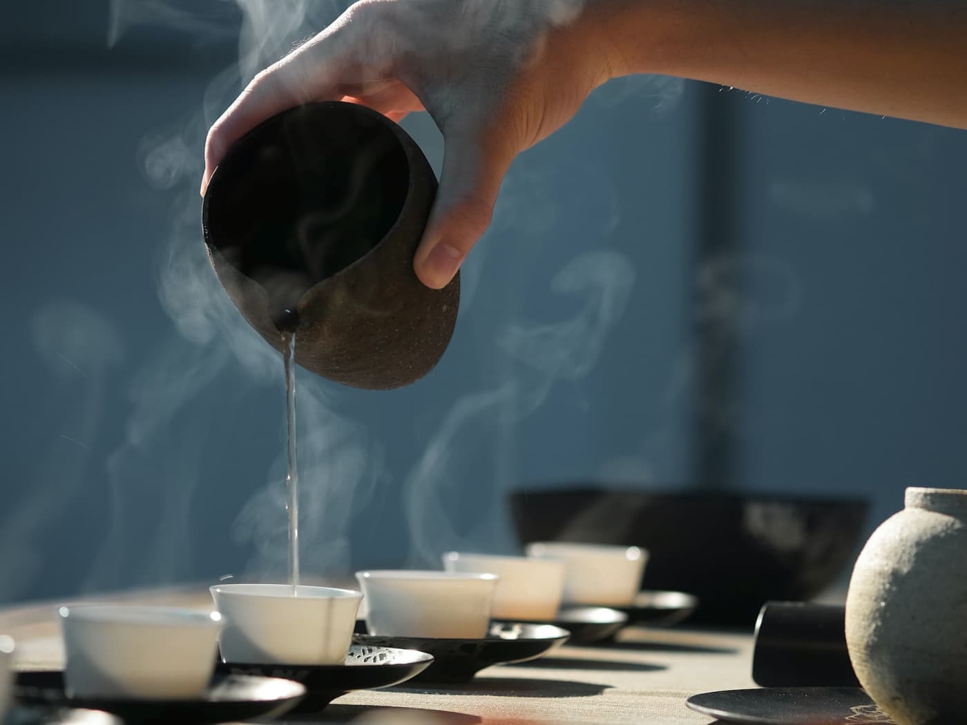 Hot water is poured onto tea in teacups