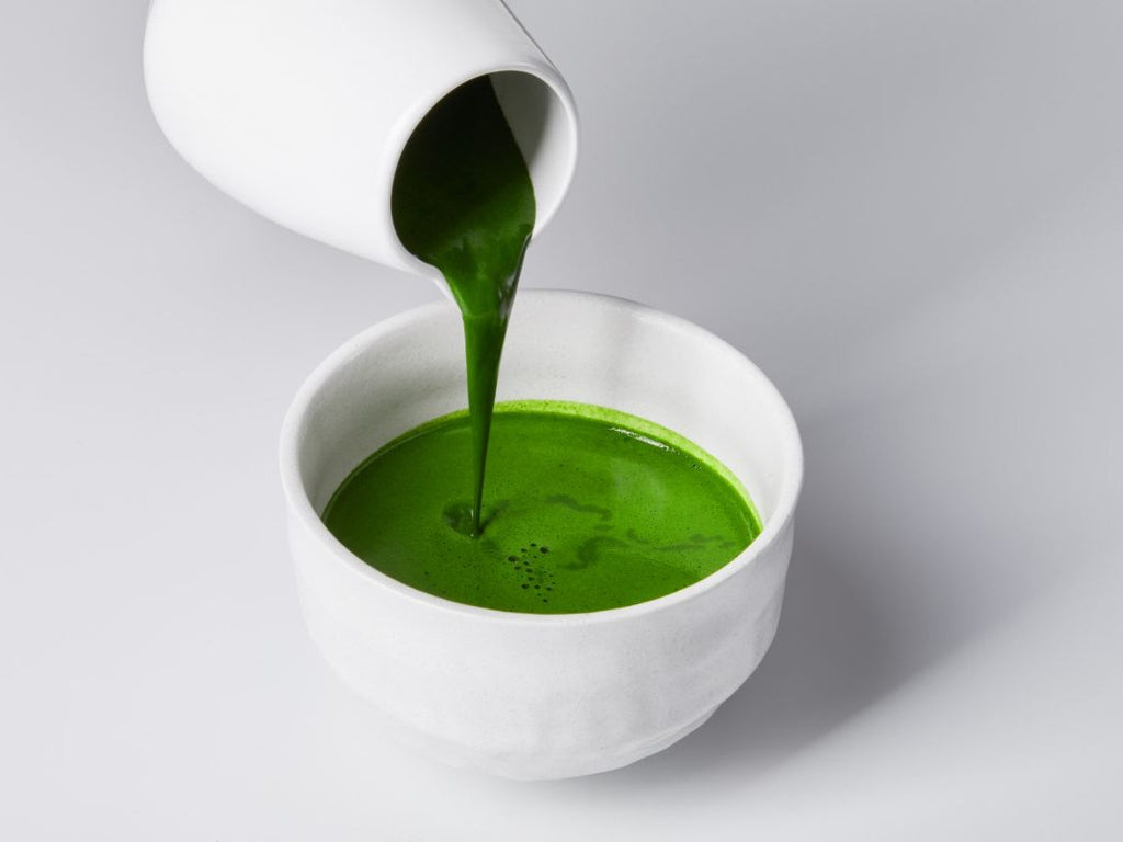 Ready-made matcha tea is poured from a teapot into a bowl