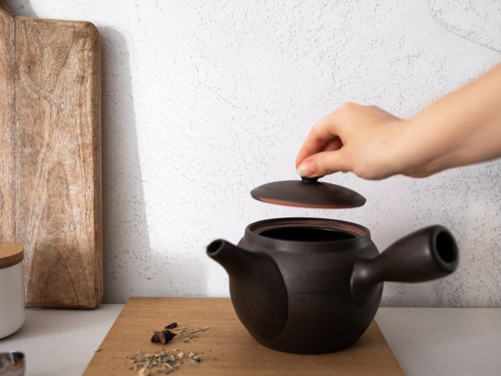 Hand holding green tea pot