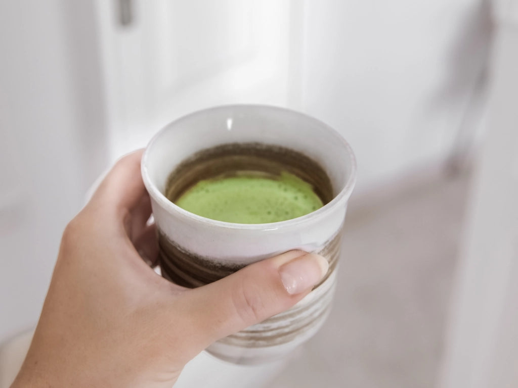 Mano con taza de matcha