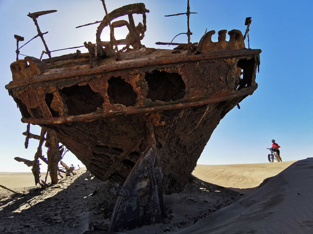 Riding fat bike past ship wreck in Namibia