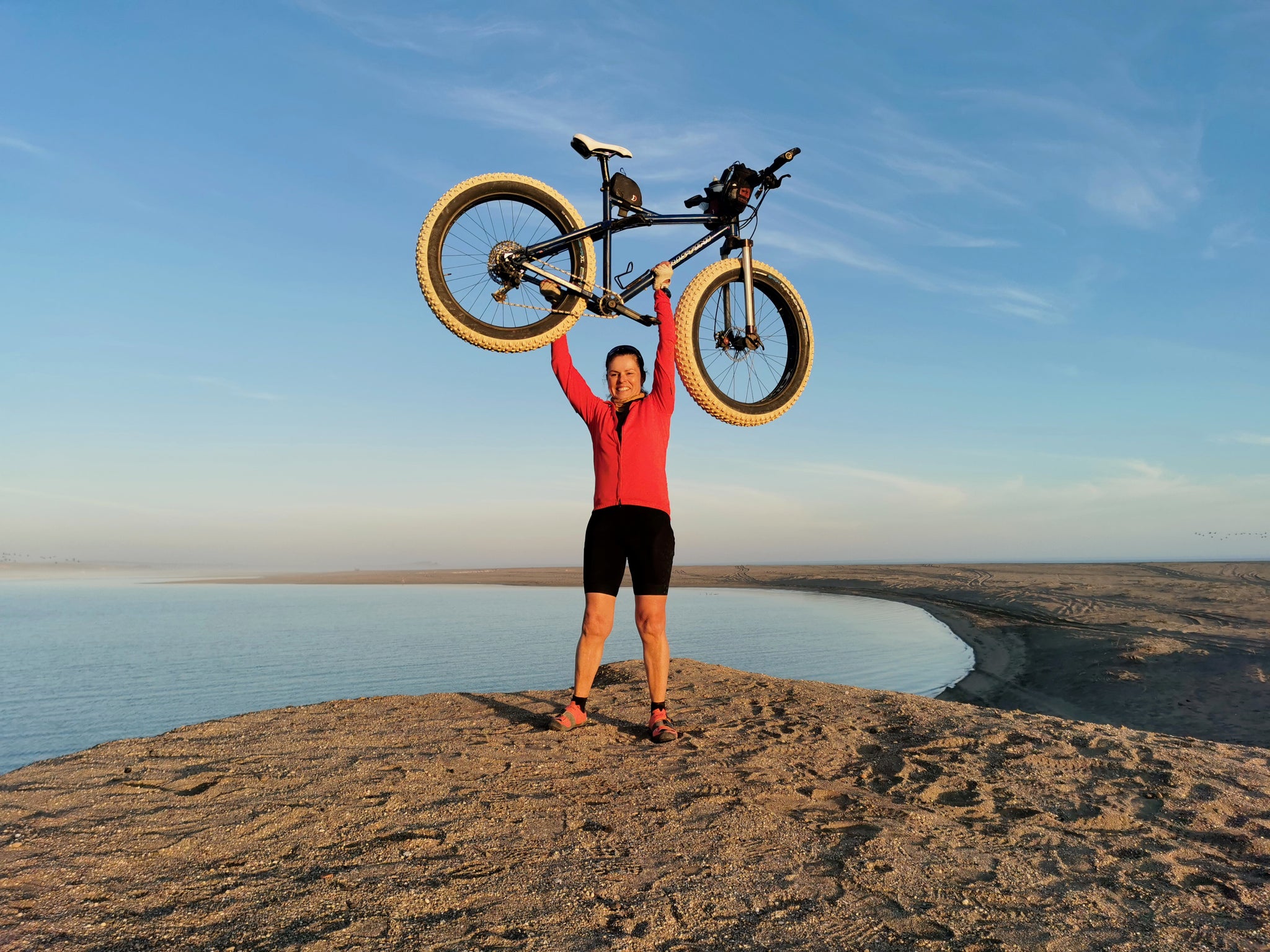 Holding bike over head atop of the mountain 