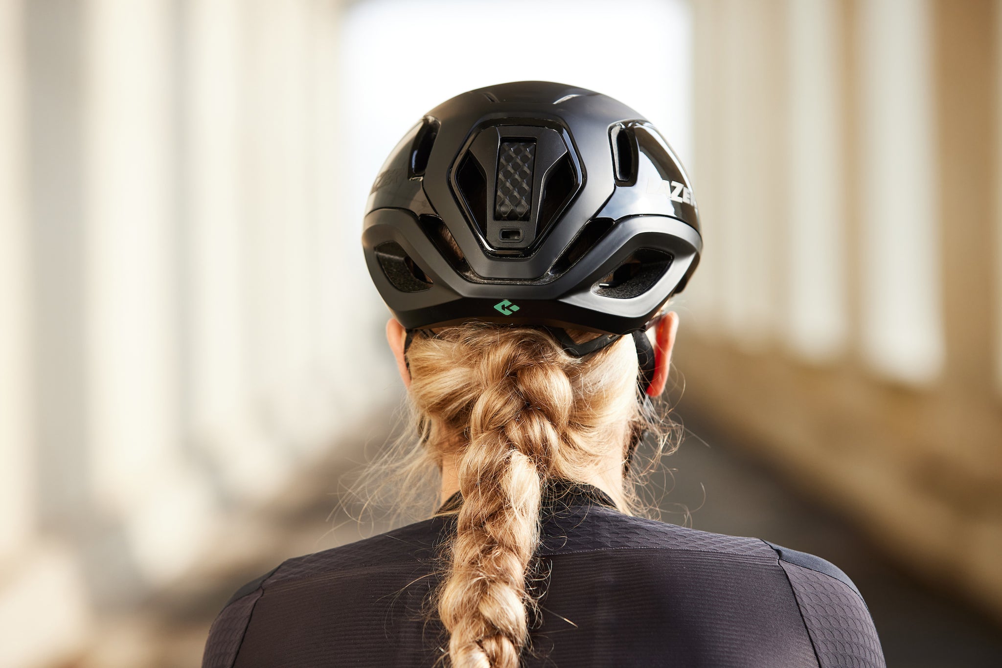 Back of a females head with a pony tail wearing a Lazer vento KinetiCore bicycle helmet 