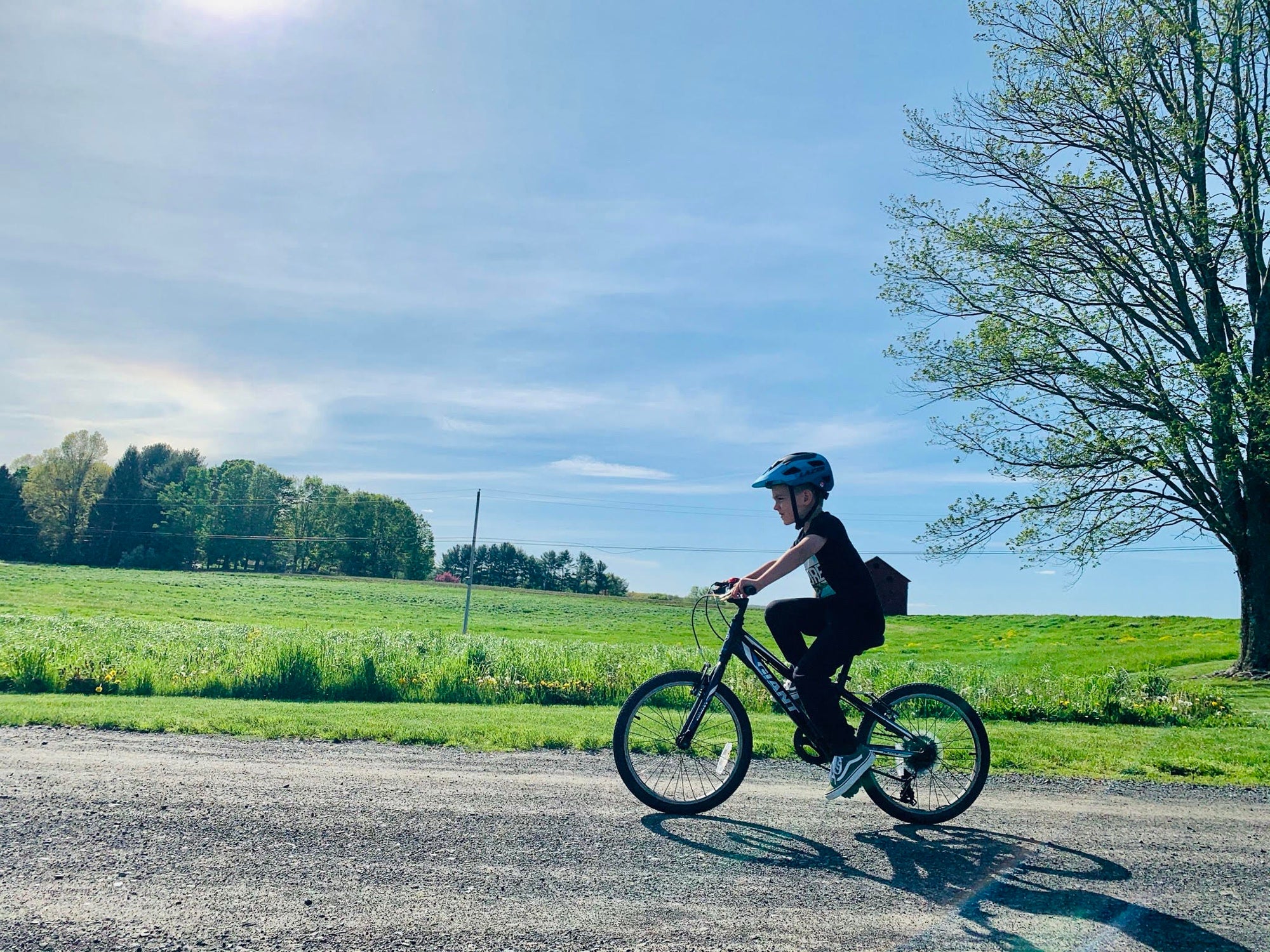 Young kid riding his bike with a Lazer kids helmet on a sunny day while riding his bicycle