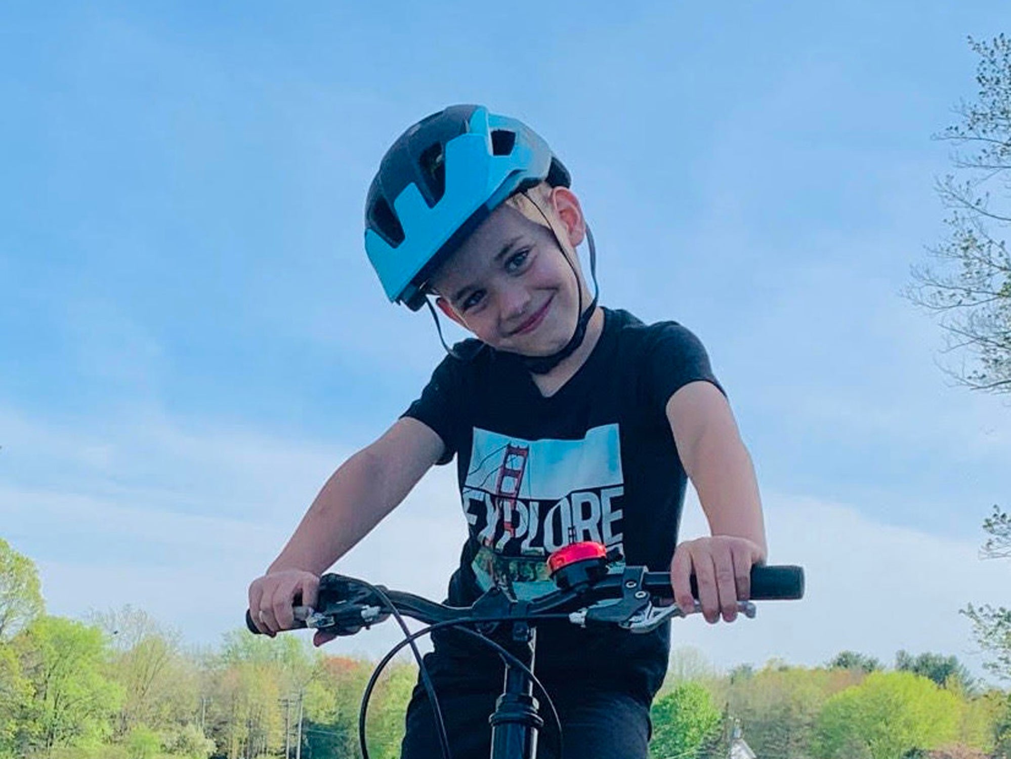 Young boy smiling as he ridings his bike while wearing a Lazer Kids helmet