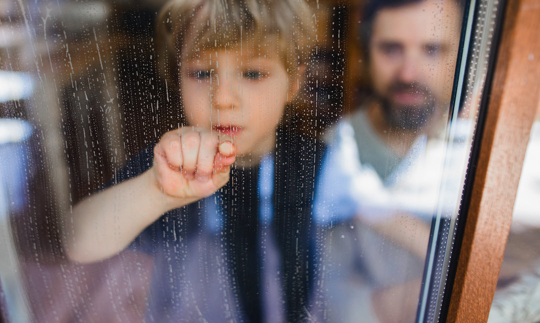 Kind hinter dreckigem Fenster