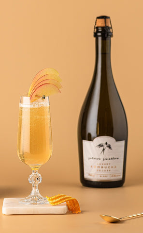 Sparkling Spicce non-alcoholic cocktail garnished with an apple fan beside a bottle of Silver Swallow luxury kombucha