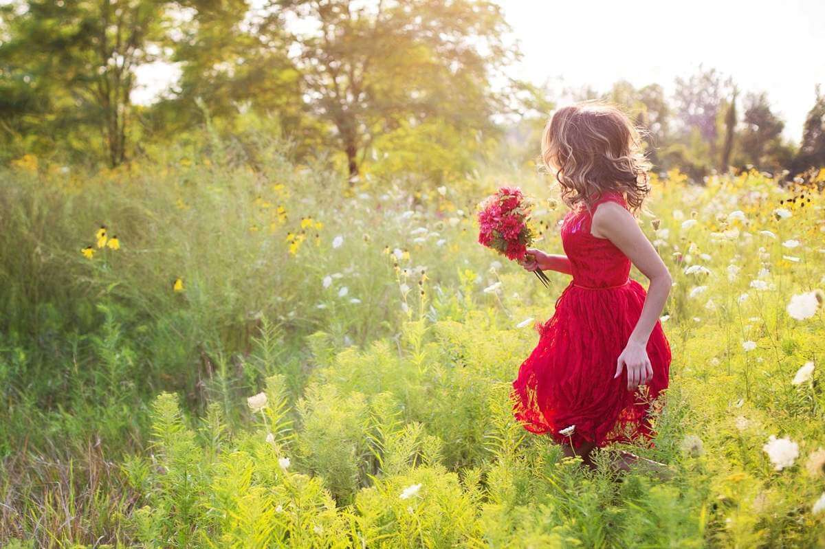 Maman en robe rouge dans le champ avec un bouquet de fleurs