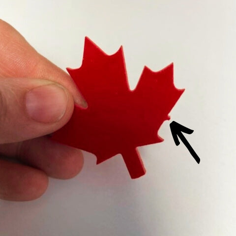 A glass precut maple leaf with the tab shown by an arrow