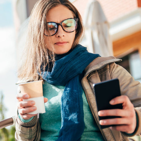 Person using a phone and holding a coffee cup