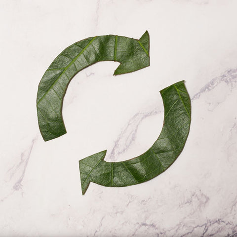 A textured background with green circular arrows cut out of leaves