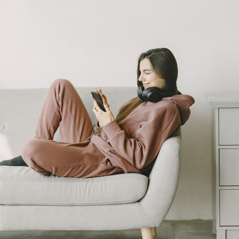 Person sitting on a couch while using a smartphone