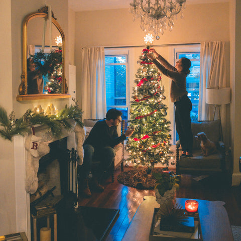 two people decorating a Christmas tree in the living room