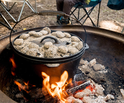 Dutch oven in fire pit with coals on top