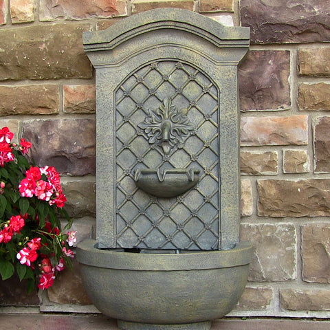 Wall fountain hanging from a brick wall outside.