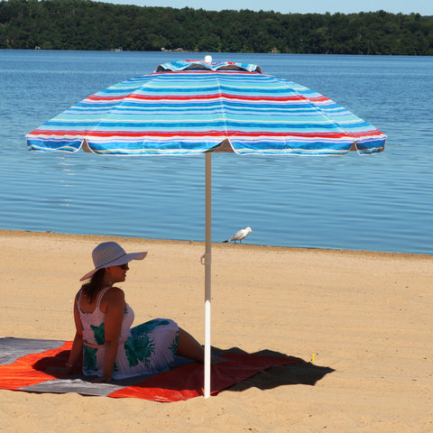 woman laying in the sand on a beach with an umbrella shading her