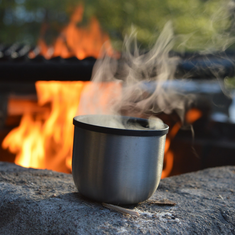 Getting ready to cook over a campfire with a cup of coffee in the morning.