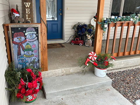 3 porch pots decorated on the porch with garland on the railing