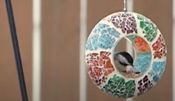 Bird eating at a mosaic glass fly-through bird feeder