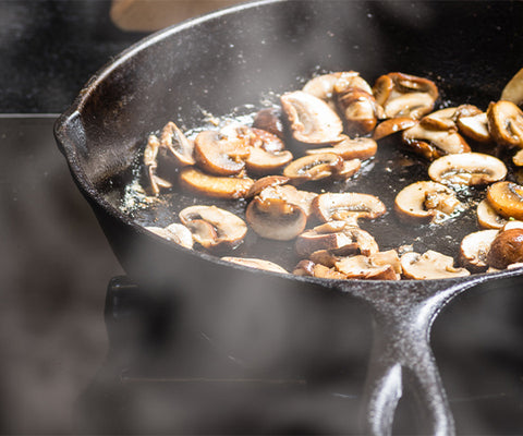 mushrooms cooking in a cast iron pan on the stove